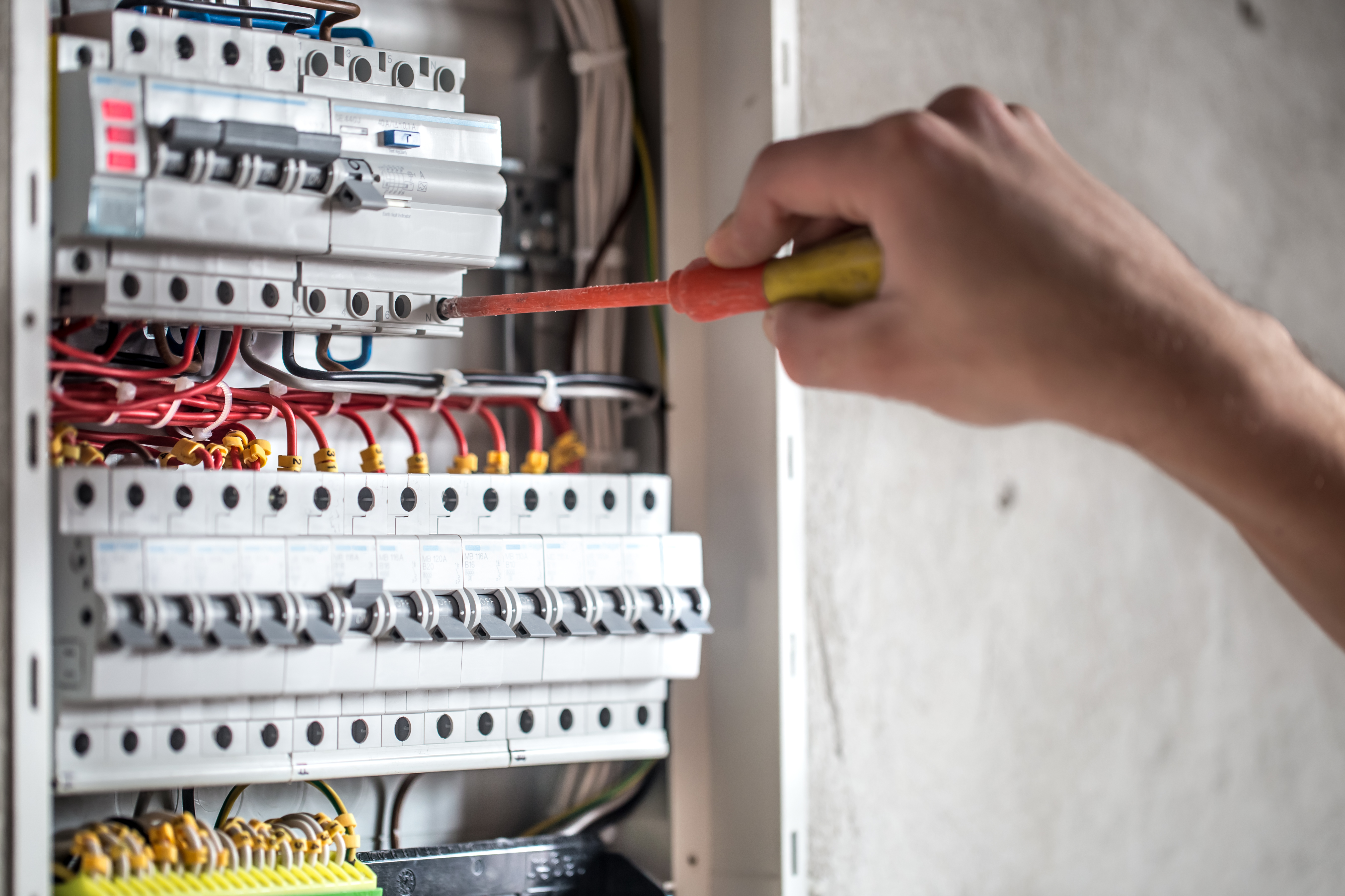 man-an-electrical-technician-working-in-switchboard-with-fuses-installation-and-connection-of-electrical-equipment-close-up
